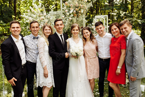 the newlyweds are photographed with family and friends. large group of people. A beautiful bride with a handsome groom is photographed with guests of different ages and nationalities against 