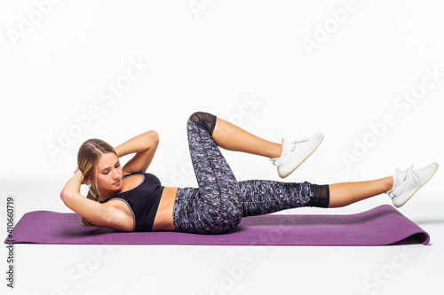 Portrait of young attractive woman doing exercises. Brunette with fit body on yoga mat.