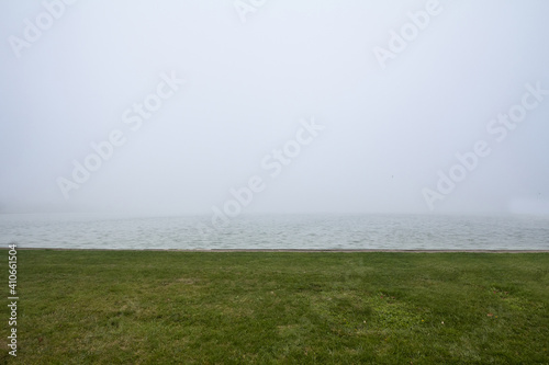 Smoggy fog in winter on the Palic Lake, in Subotica, Serbia, the green grass of the shore is visible. Also known as Palicko Jezero, it is one of the main attractions of Vojvodina province