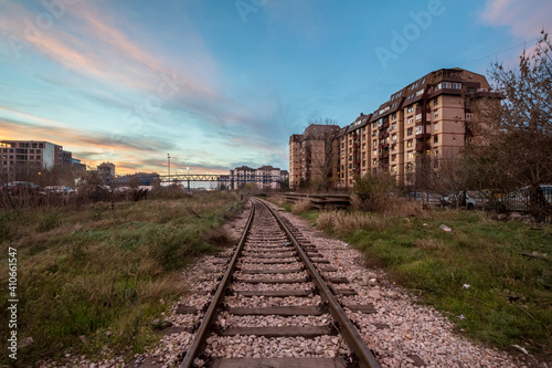 urban Industrial landscape at dusk, in a sunset evening, in Belgrade, Serbia, with a single railway track passing in the middle of industries while the chimney of a factory can be seen in background.