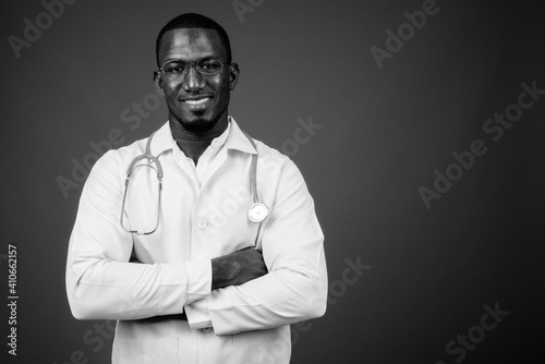 Handsome African man doctor wearing eyeglasses against brown background