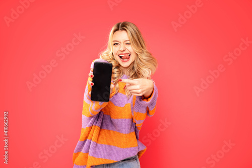 Happy blonde caucasian woman showing empty mobile phone screen.