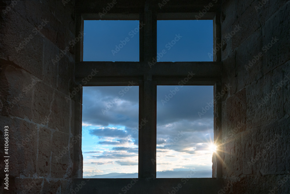French winter landscapes. Sunlight shining through a cross shaped window. Ruins of Crussol. View to the Vercors mountains and the clouds.