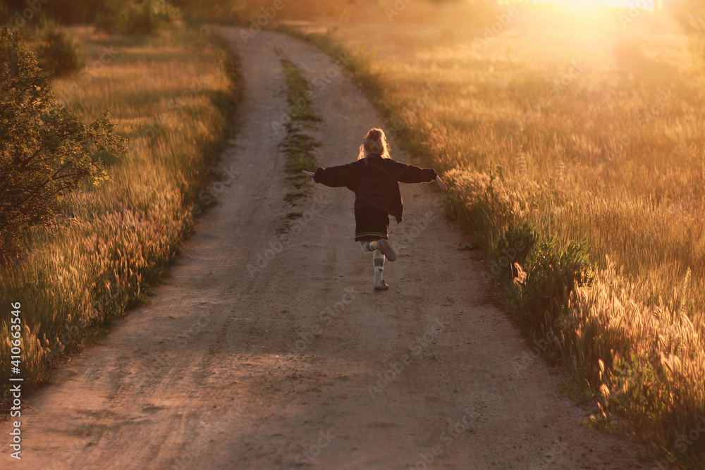 A girl runs along a road drenched in sun at sunset. Beautiful landscape.