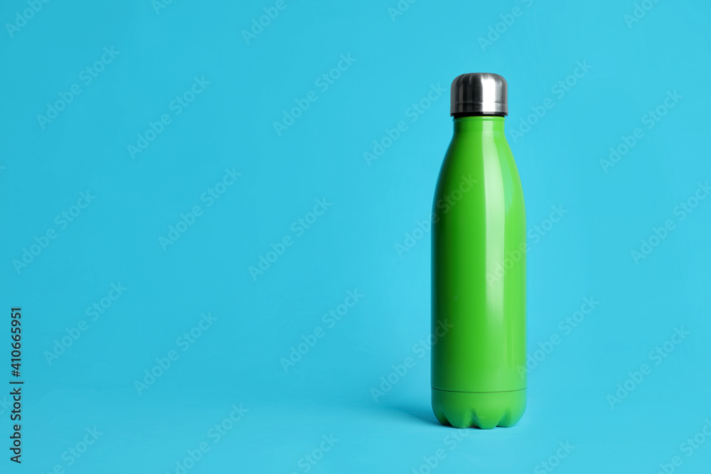 Stylish thermo bottle on light blue background, space for text Stylish thermo bottle on light blue background, space for text