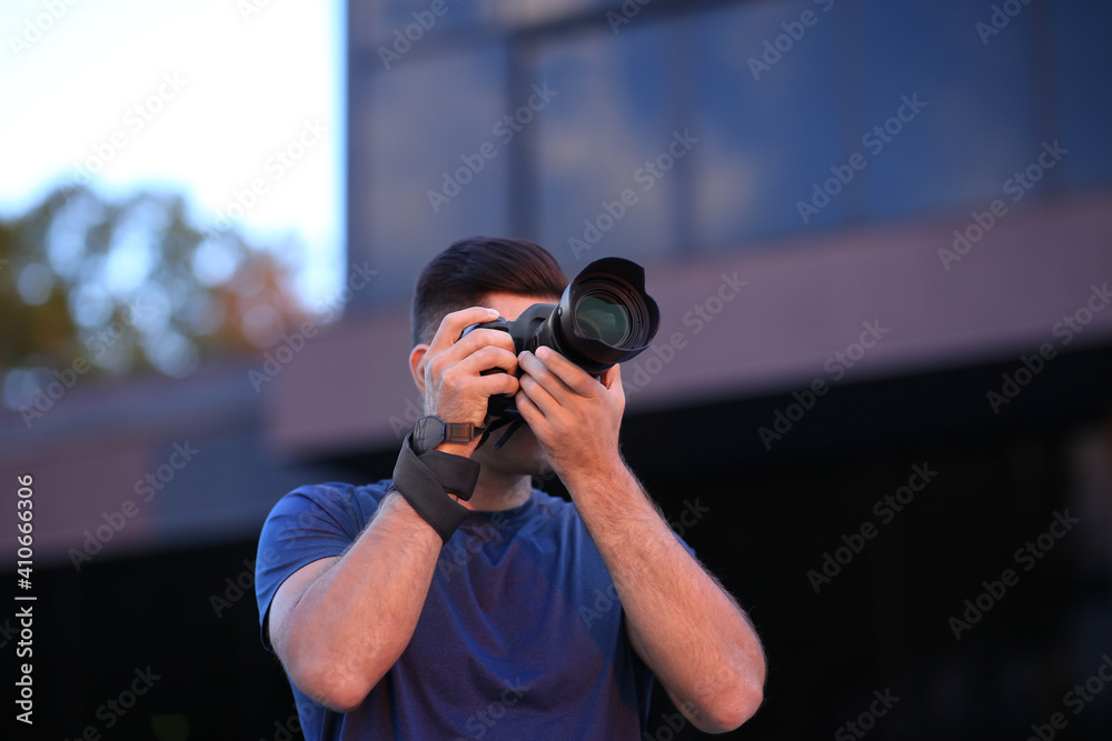 Photographer taking picture with professional camera on city street in evening Photographer taking picture with professional camera on city street in evening
