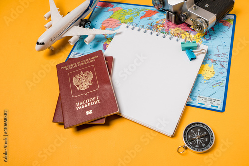 Open notebook with space for text on travel accessories on a yellow background. Planning your summer vacation, travel, and vacation. Russian passports.