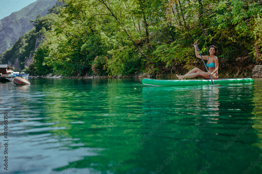 Female on stand up paddle board on beautiful lake Female on stand up paddle board on beautiful lake