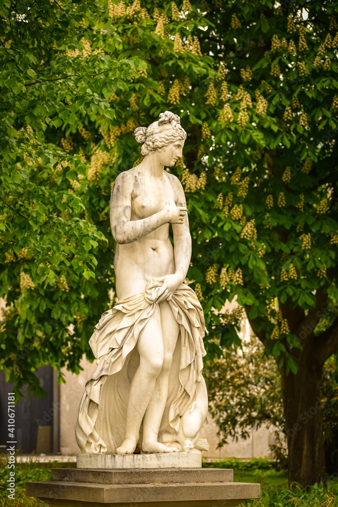 Sculpture of a woman against the background of a flowering chestnut tree in a city Park