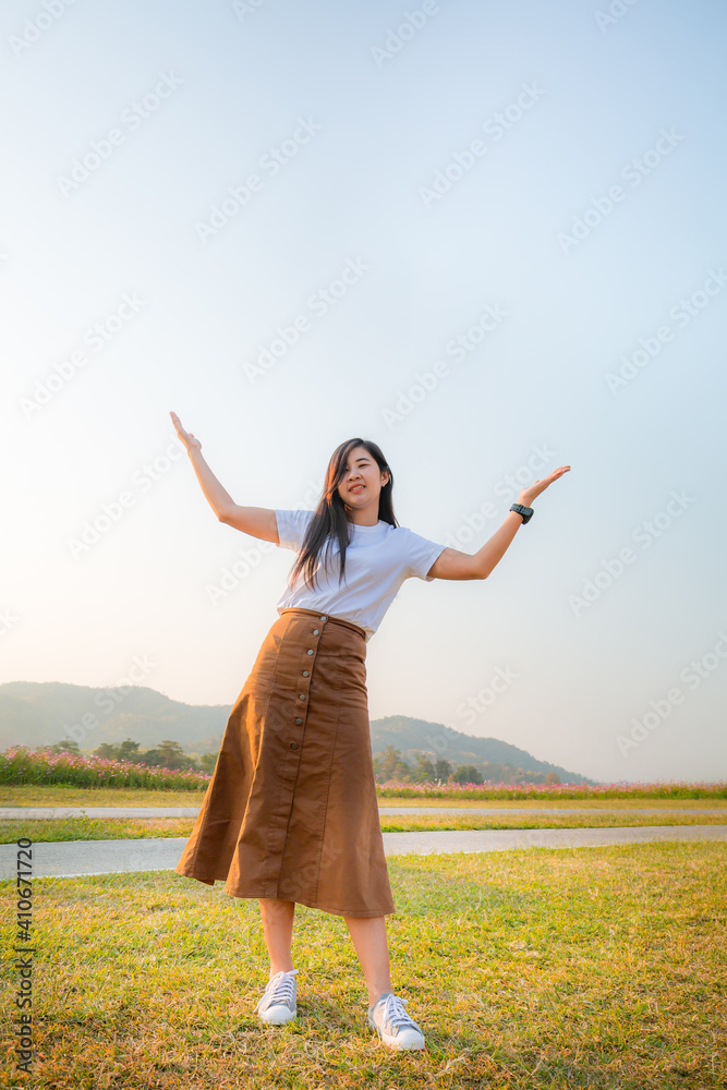 Young woman in white dress standing on green grass over blue cloudy sky background Young woman in white dress standing on green grass over blue cloudy sky background
