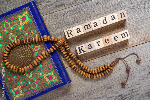 Foto Holy Al Quran with written arabic calligraphy meaning of Al Quran and rosary beads or tasbih on shabby wooden board