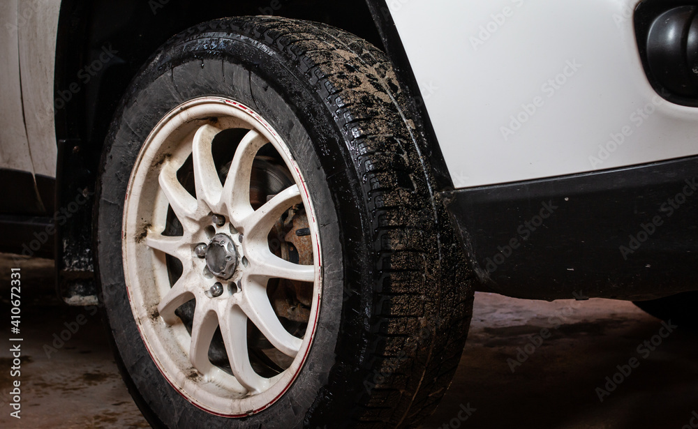 February 2021: Muddy snow tires on a white SUV, white rim and slight vignette, Toronto, Ontario, Canada. 
