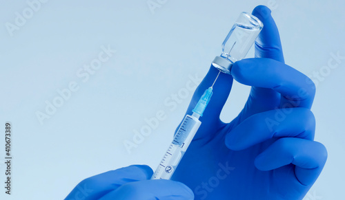Doctor hands holding a vaccine bottle and syringe,beginning of worldwide mass vaccination for coronavirus COVID-19,influenza or flu,world immunization concept. Selective focus