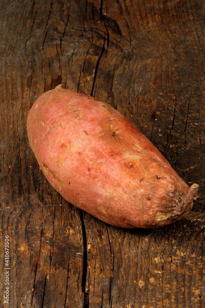Raw sweet potato or batatas on old wooden board. Batatas on wooden surface Raw sweet potato or batatas on old wooden board. Batatas on wooden surface