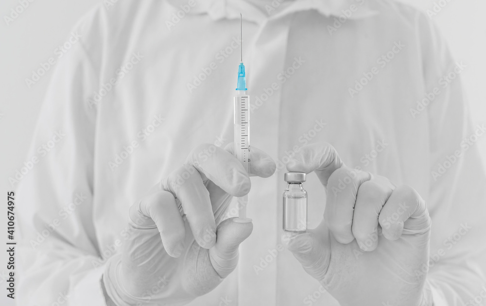 Doctor hands holding a vaccine bottle and syringe, beginning of worldwide mass vaccination for coronavirus COVID-19, influenza or flu, world immunization concept. Selective focus Doctor hands holding a vaccine bottle and syringe, beginning of worldwide mass vaccination for coronavirus COVID-19, influenza or flu, world immunization concept. Selective focus