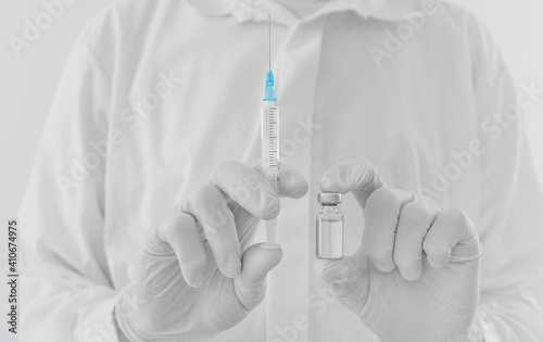 Doctor hands holding a vaccine bottle and syringe, beginning of worldwide mass vaccination for coronavirus COVID-19, influenza or flu, world immunization concept. Selective focus