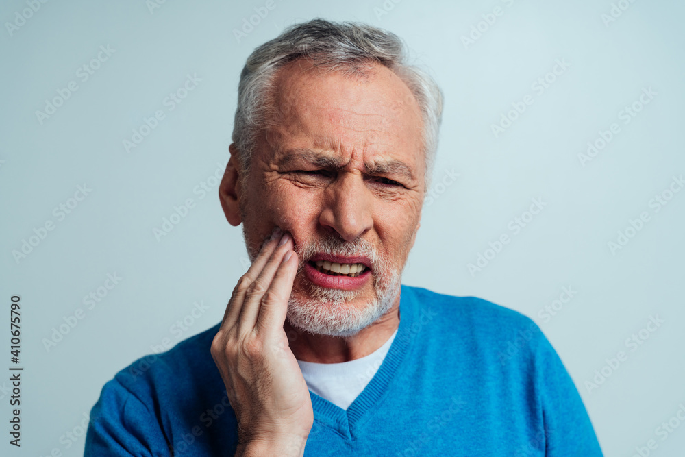 Handsome senior isolated on grey background. Old man feeling pain. Concept about the third age and seniority Handsome senior isolated on grey background. Old man feeling pain. Concept about the third age and seniority
