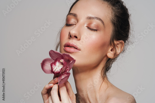 Sensual half-naked woman posing with orchid on camera