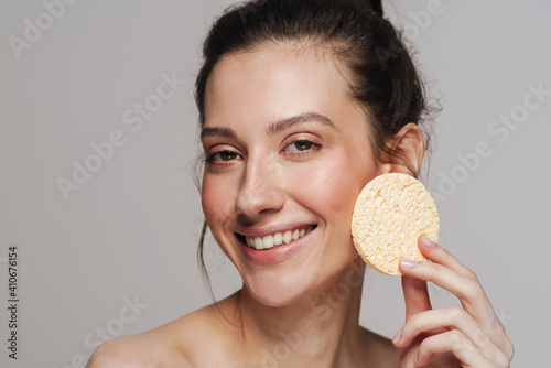 Happy half-naked woman smiling and using cosmetic sponge