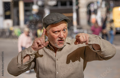 Ein älterer Mann mit Mütze gestikuliert mit den Händen und redet