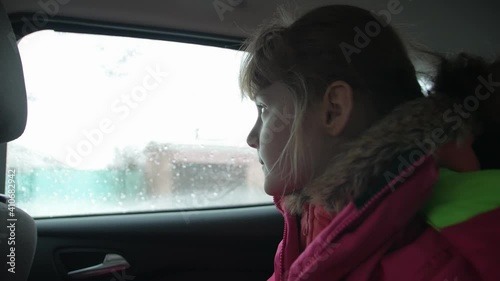 Little girl in car rides rain outside the window