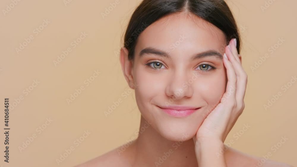 Beauty portrait of young dark-haired woman who looks at camera and puts her head on her hand Beauty portrait of young dark-haired woman who looks at camera and puts her head on her hand