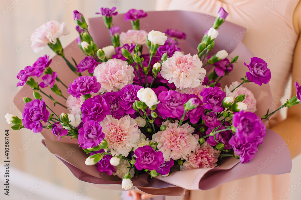 Beautiful spring bouquet of purple carnations in the hands of a young woman for a gift