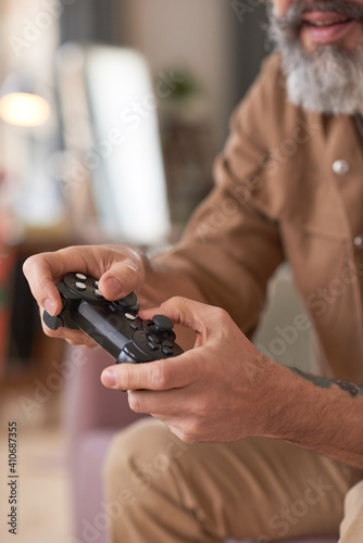 Close-up of mature man pushing buttons on joystick playing video games