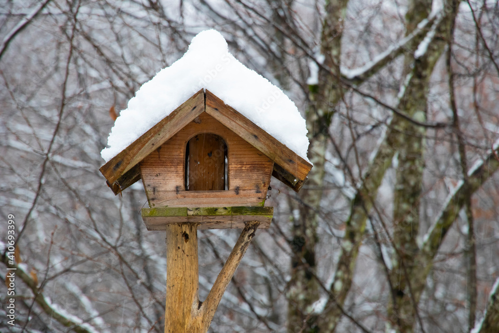 Snow-covered wooden bird feeder in the woods. Winter time. Bird food. Snow-covered wooden bird feeder in the woods. Winter time. Bird food.