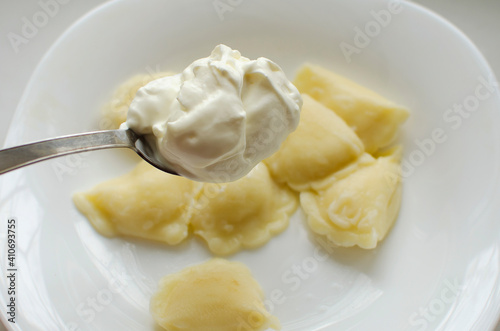 Put sour cream in stuffed dumplings. Traditional Russian home cooking.