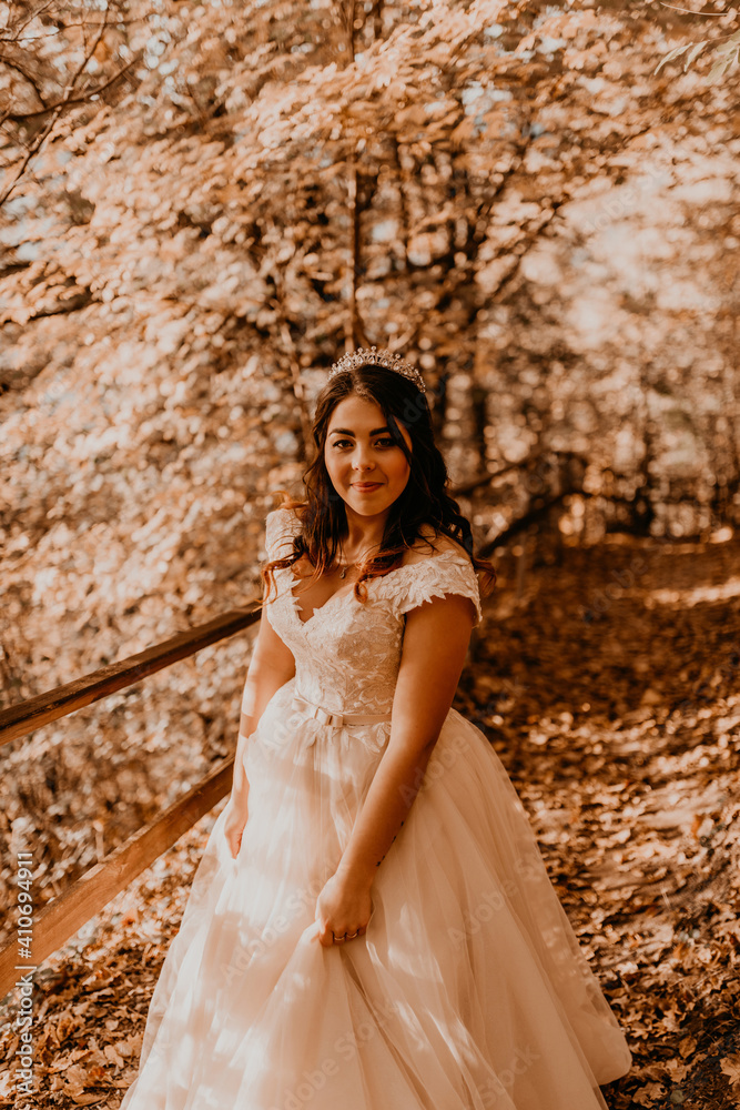 bride in white wedding dress walks through autumn forest on fallen orange leaves bride in white wedding dress walks through autumn forest on fallen orange leaves