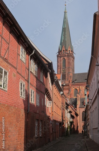 The St Nicolai church, built in the 14th century in brick gothic style, and small alley with historic brick stone houses. In the old town of Lüneburg, North Germany, Europe