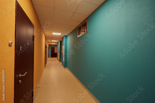 ypical ordinary corridor of a residential building, painted in bright colors, metal unnamed apartment doors, rich shades photo