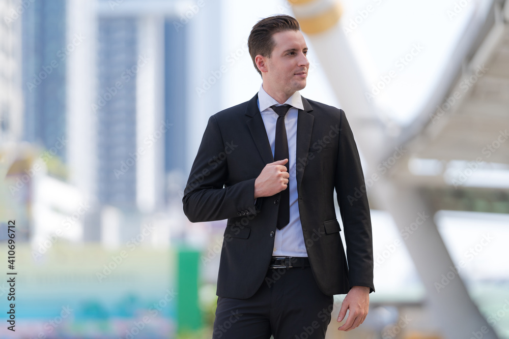 Portrait of successful businessman standing in front of modern office buildings