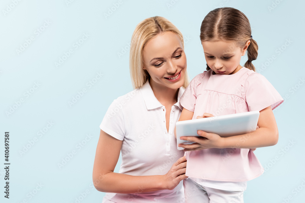 happy mother and daughter looking at digital tablet isolated on blue happy mother and daughter looking at digital tablet isolated on blue
