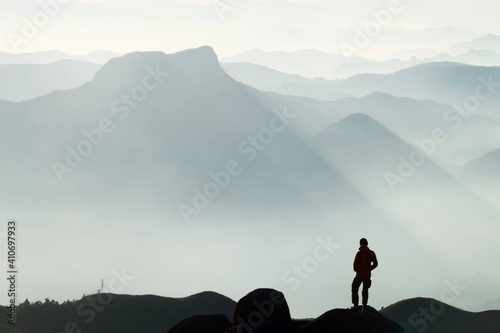 A young man stood looking at the mist surrounding the mountain ahead.