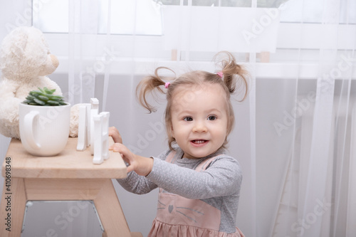 funny toddler girl playing with toys at home in white room