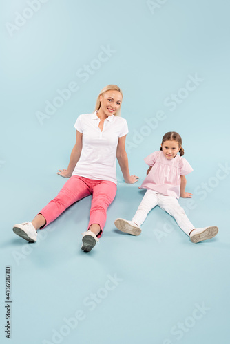 full length of happy mother and kid sitting on blue