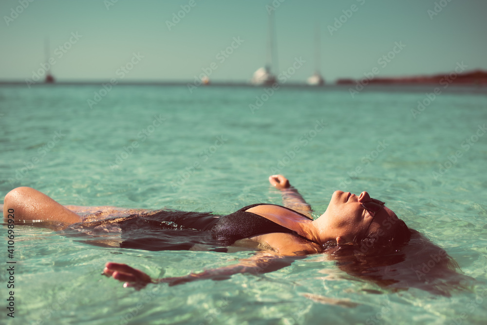 Women with sunglasses and swimwear in the blue ocean sea on bright sunny day in Menorca