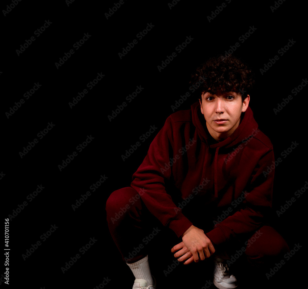 Attractive young man with curly hair posing on black studio background