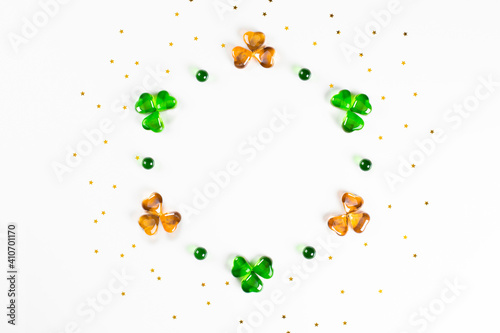 Foto Circle frame of green and orange glass hearts shamrocks lying on white background with sparse gold stars confetti Happy St