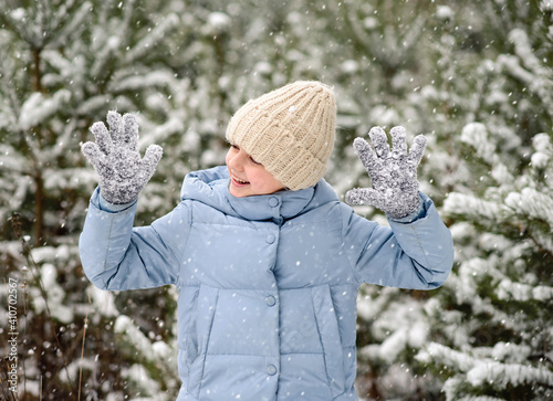 Happy little girl playing with snow in beautiful winter forest. Walking and active rest in winter