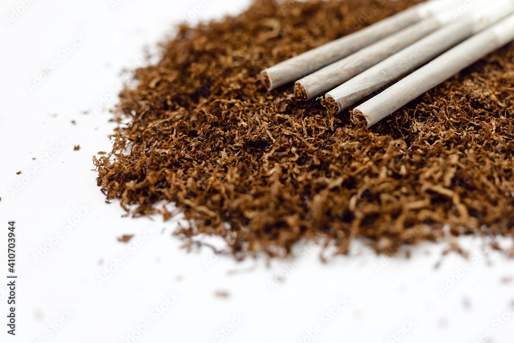 A pile of dry tobacco with rolled cigarettes isolated on a white A pile of dry tobacco with rolled cigarettes isolated on a white
