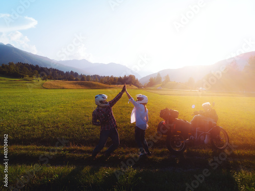 A couple of motorcyclists pose of the incredible beauty of the sunset. Sun rays and glare. Happy Riders in love guy and girl. Bikers and their bike. destination. Mountains of Slovenia. © Sergey