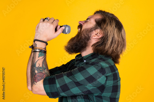 rock music festival. vocal school. brutal and rock. bearded man wear checkered shirt singing song. male singer with mic. concept of karaoke. man singer love music. brutal man sing with microphone