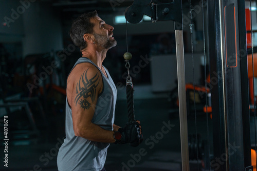 Bodybuilder doing cable tricep pushdowns during his workout in the gym