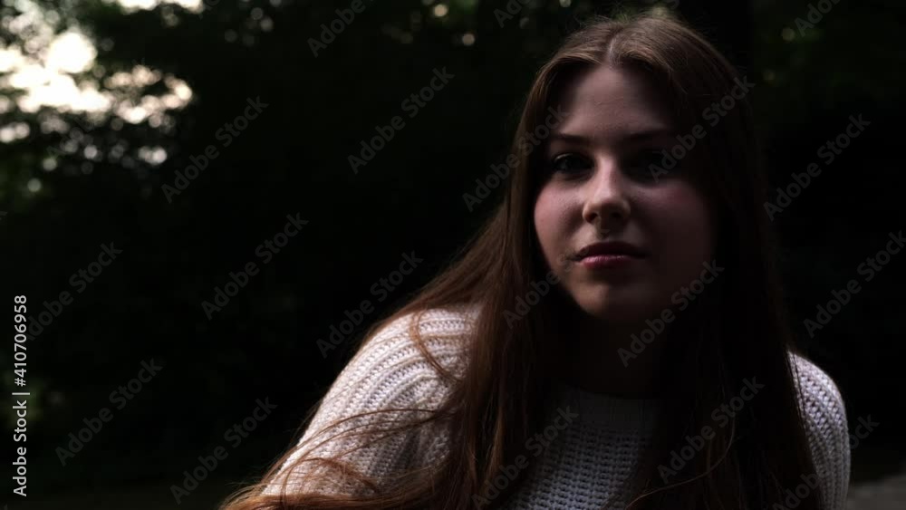 [4k] slow motion portrait of cute yount woman sitting outdoors ranting out of nothing before starting to laugh