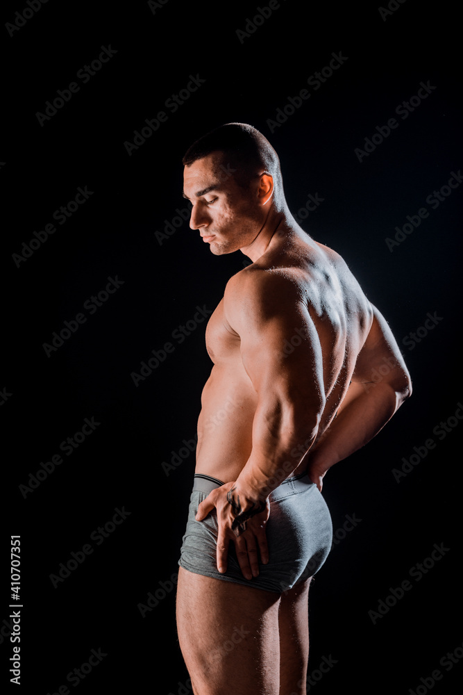 Young bodybuider with tattoos posing in studio