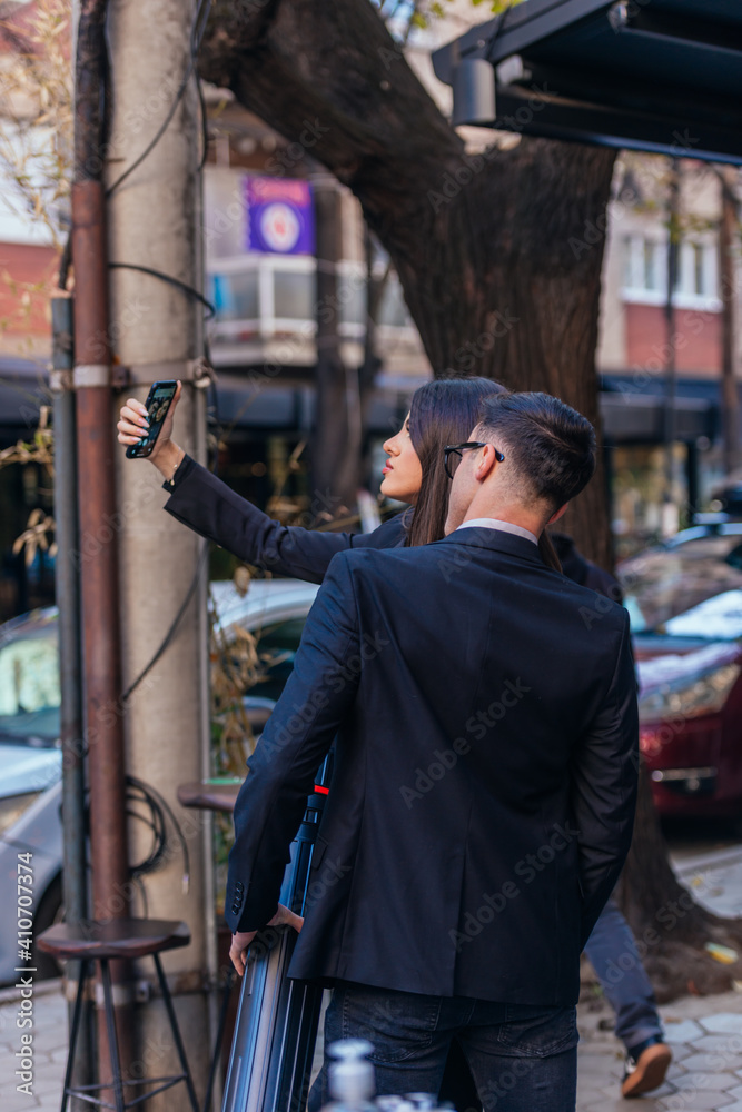 Back view of two business people making a selfie on the streets. Back view of two business people making a selfie on the streets.