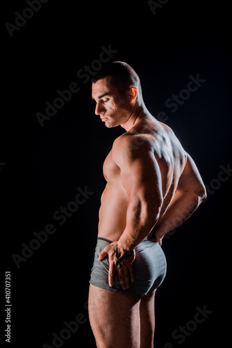 Young bodybuider with tattoos posing in studio